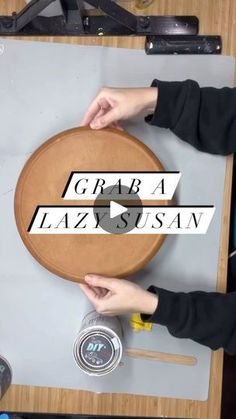 two people are working on a wooden table with scissors and tape around the edges that read grea lazzy susan