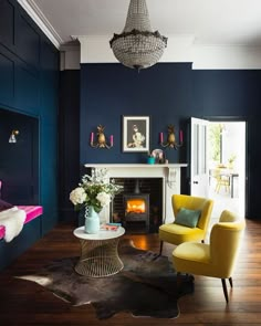 a living room filled with furniture and a fire place under a chandelier hanging from the ceiling