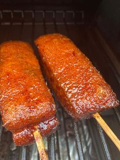 two meat skewers are cooking on the grill