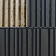 the side of a building with black metal sidings and wood slats on it