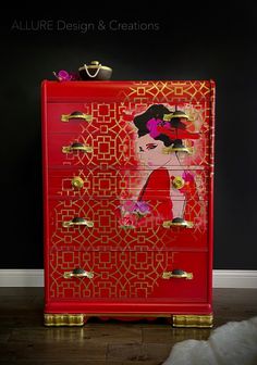 a red dresser with gold handles and designs on the drawers is next to a white furnishing