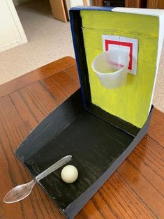 an odd looking object with a spoon and cup in it on a wooden table top