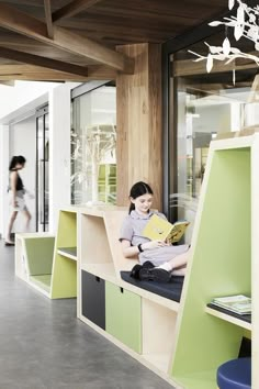 a young boy sitting on top of a book shelf