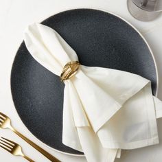 a black plate with white napkins and gold forks