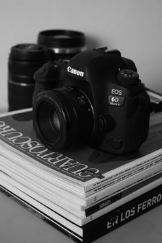 a camera sitting on top of a stack of books next to two other cameras in black and white