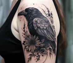 a woman's arm with a black bird and flowers tattoo on her left shoulder