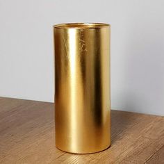 a gold vase sitting on top of a wooden table