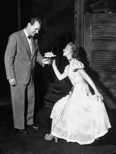 an old black and white photo of a man feeding a woman something from her hand