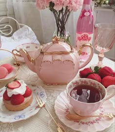 a table topped with plates and cups filled with desserts next to pink vases