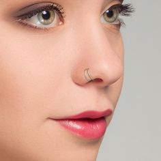 a close up of a woman's face with nose piercings on her nose