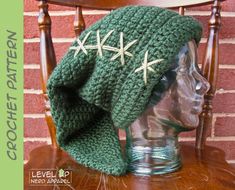 a crocheted green hat with white stars on it sitting on top of a wooden chair