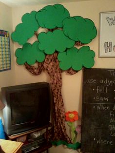 a classroom with a blackboard and a tree on the wall next to a television