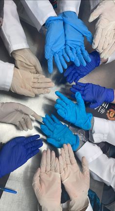 many hands in blue and white gloves are arranged in a circle