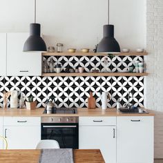 a kitchen with black and white tile backsplash, wooden counter tops, and hanging lights