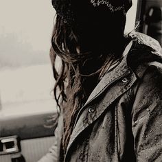 a woman sitting in the back seat of a car wearing a beanie and looking at her cell phone