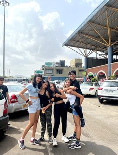 four young people posing for a photo in front of a parking lot