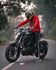 a man wearing a helmet and sitting on a motorcycle in the middle of the road