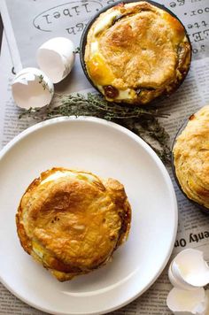 two pies sitting on top of a white plate next to an egg muffin