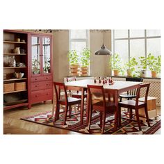 a dining room table and chairs in front of a bookcase with potted plants