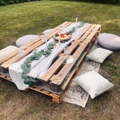 a table made out of wooden pallets with white linens and greenery on top