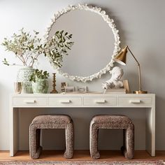 two stools sit in front of a white dresser with a mirror on the wall