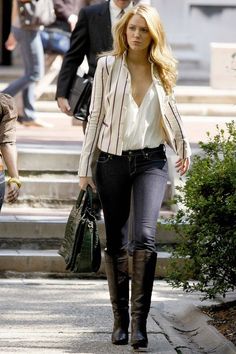 a woman walking down the street carrying a handbag and wearing high heeled boots