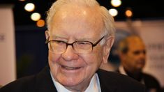 an older man wearing glasses and a suit smiling at the camera while standing in front of a crowd