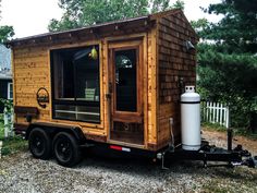 a tiny house on wheels is parked in the gravel