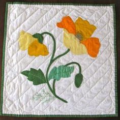 a quilted wall hanging with yellow and orange flowers painted on it's sides