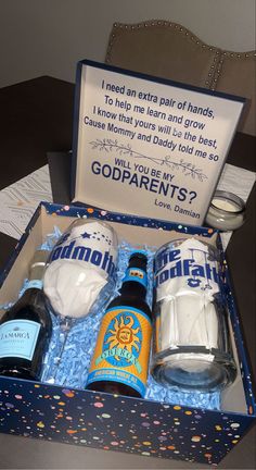 an open box containing two bottles of beer and some confetti on the table