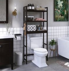 a white toilet sitting next to a bath tub in a bathroom under a painting on the wall