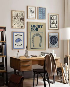 a home office with posters on the wall above it and a desk in between two chairs