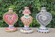 three colorful vases sitting on top of a table next to each other with hearts painted on them