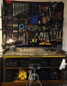 a workbench with many tools hanging on the wall