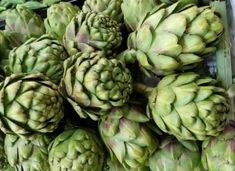 a bunch of green artichokes stacked on top of each other