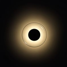 a black and white photo of a circular light in the dark room with only one light on