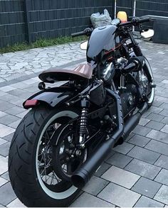 a black motorcycle parked on top of a brick road