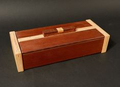 a wooden box sitting on top of a black table next to a pair of scissors