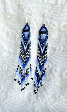 blue and black seed beaded earrings on white lace background with beads in the shape of an arrow