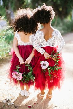 two women in red and white dresses standing next to each other with flowers on their bouquets