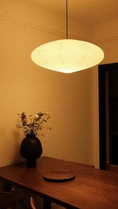 a vase with flowers sitting on top of a wooden table next to a light fixture