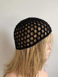 a mannequin head wearing a black netted hat with long blonde hair in front of a white wall