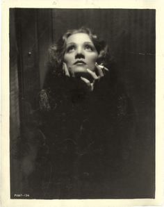 an old black and white photo of a woman with her hand on her chin looking up