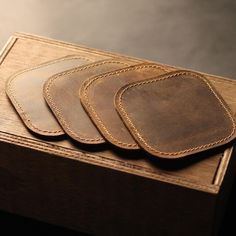 four leather coasters sitting on top of a wooden box