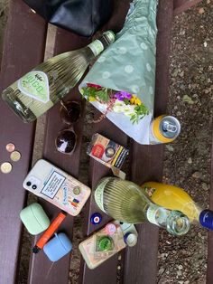 several bottles and glasses are sitting on a wooden bench next to a purse, sunglasses, and other items