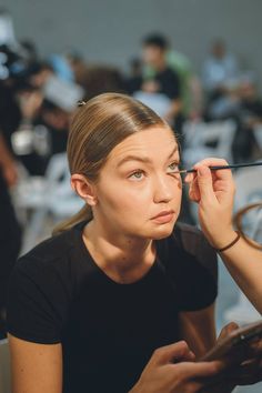 a woman is getting her make up done in front of an audience at a fashion show