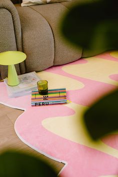 a living room with a couch, coffee table and books on the floor in front of it