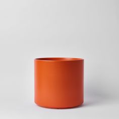 an orange cup sitting on top of a white table