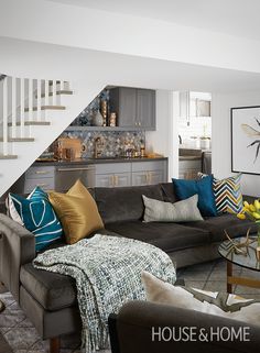 a living room filled with furniture next to a stair case and kitchen in the background