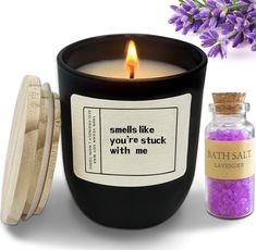 a candle that is next to a jar with some purple stuff in it and a lavender flower